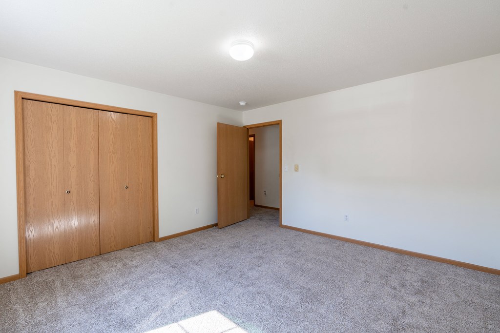 A room with two doors and carpeted floor. Fargo, ND Stonebridge Apartments