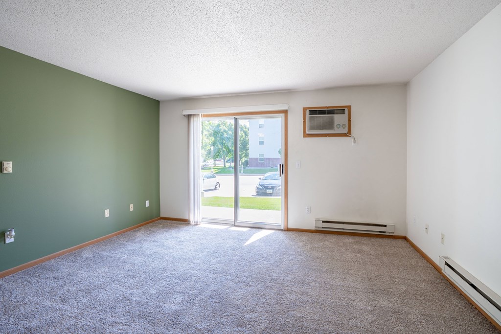 A room with a carpeted floor and a window with a view of the outside. Fargo, ND Stonebridge Apartments