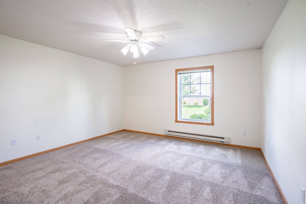 A room with a carpeted floor and a window. Fargo, ND Stonebridge Apartments