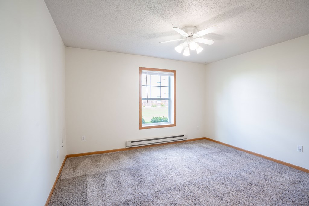 A room with a carpeted floor and a window. Fargo, ND Stonebridge Apartments