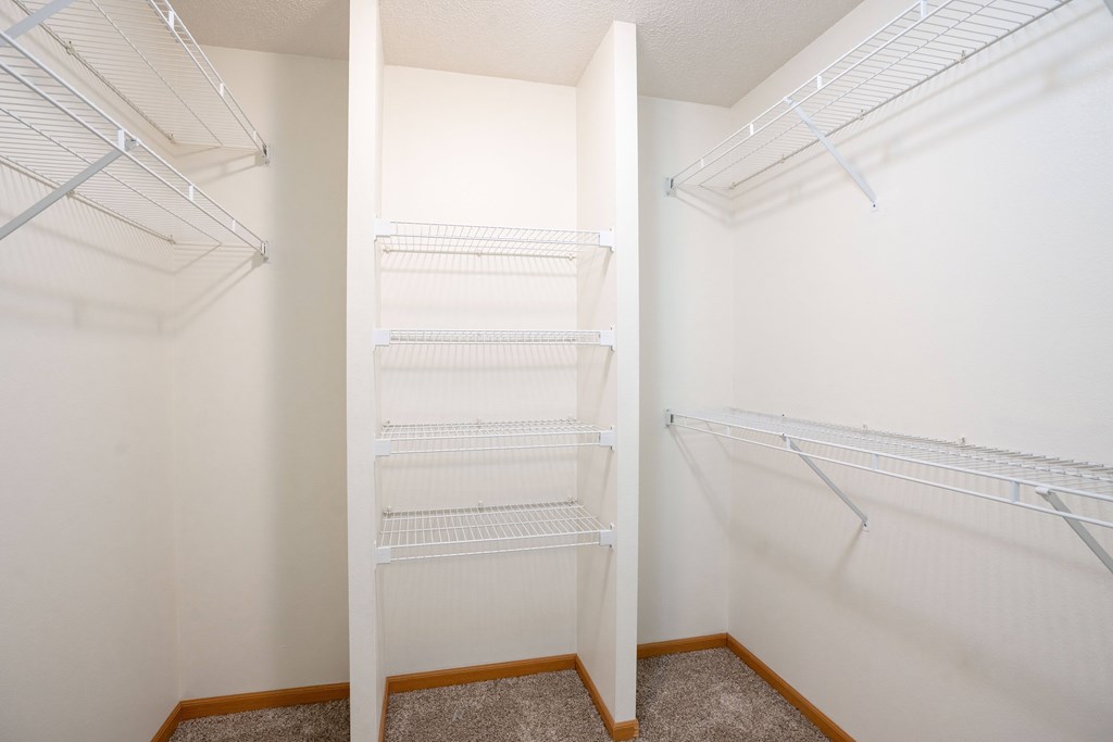 Empty white shelves in a bedrooms walk in closet. Fargo, ND Stonebridge Apartments