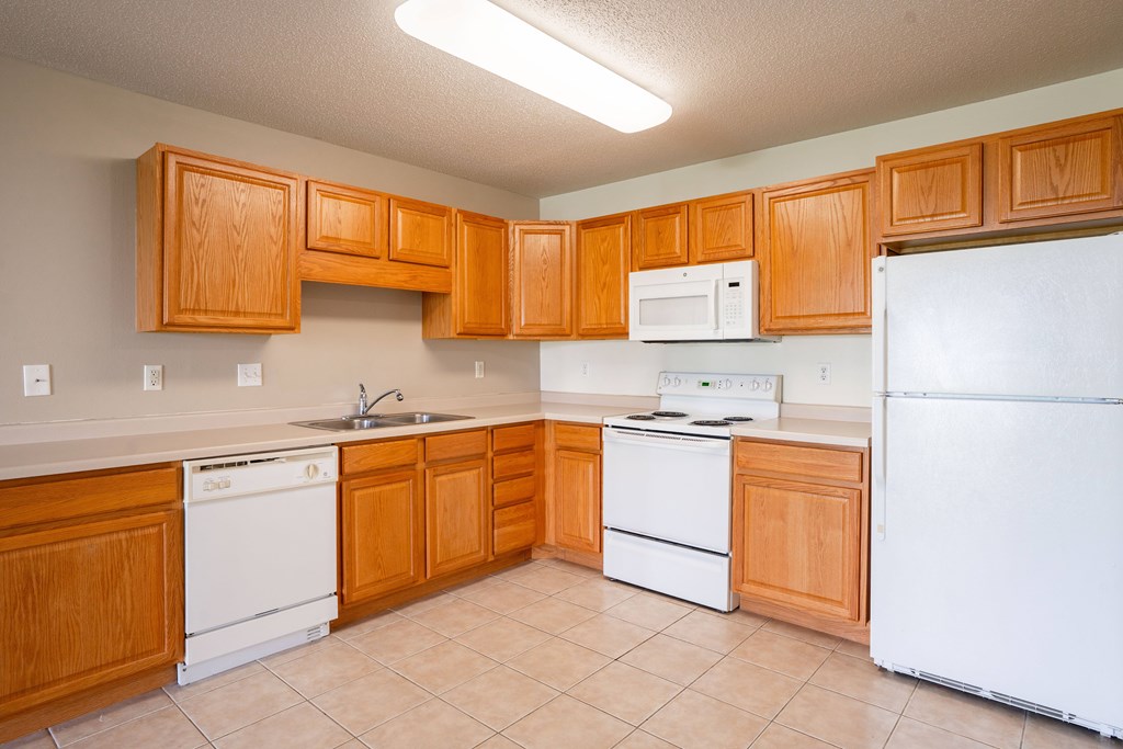 A kitchen with wooden cabinets and white appliances. Fargo, ND Stonebridge Apartments