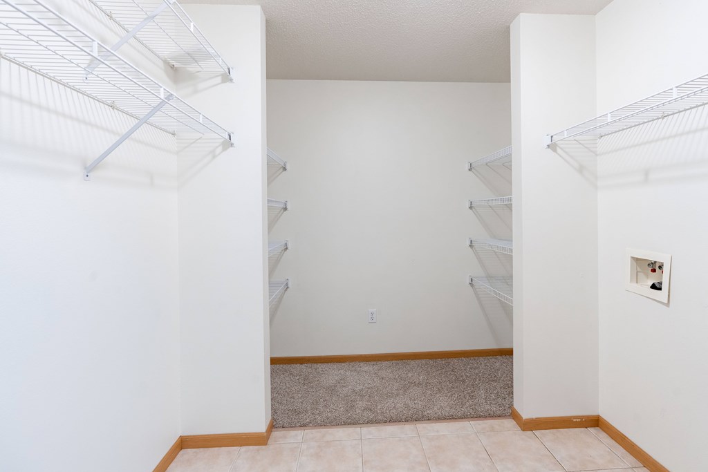 A laundry room with laundry hookups and shelves. Fargo, ND Stonebridge Apartments