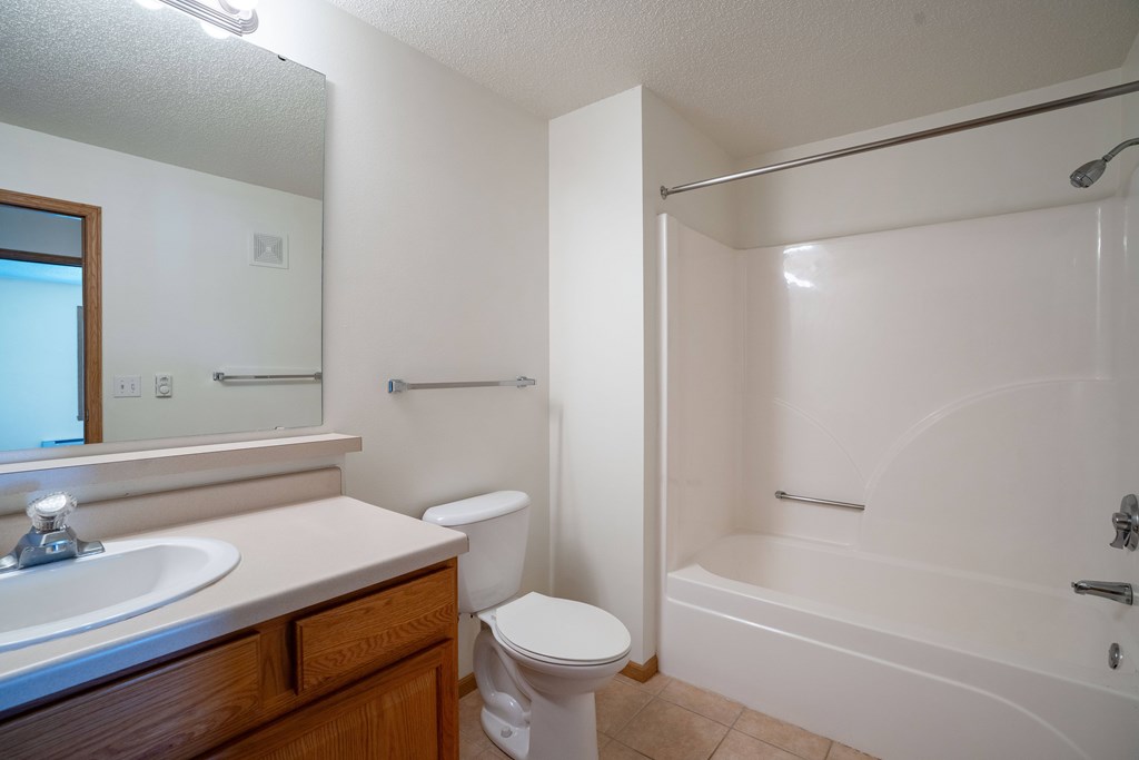 A white bathroom with a toilet, sink, and bathtub. Fargo, ND Stonebridge Apartments