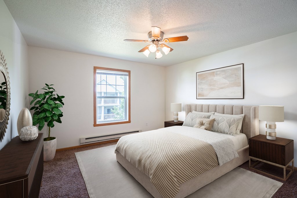 A bedroom with a large bed and a ceiling fan. Fargo, ND Stonebridge Apartments