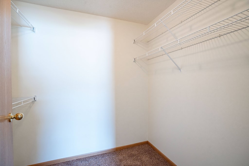 A room with a door and a brown carpet. Fargo, ND Stonebridge Apartments