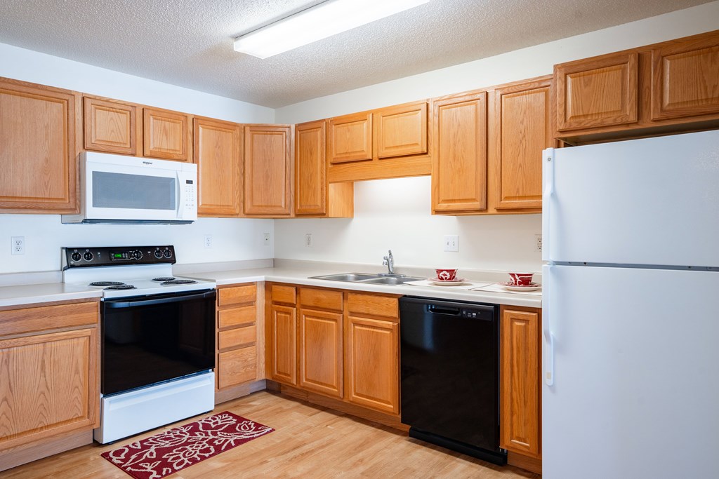 A kitchen with wooden cabinets and a white refrigerator. Fargo, ND Stonebridge Apartments