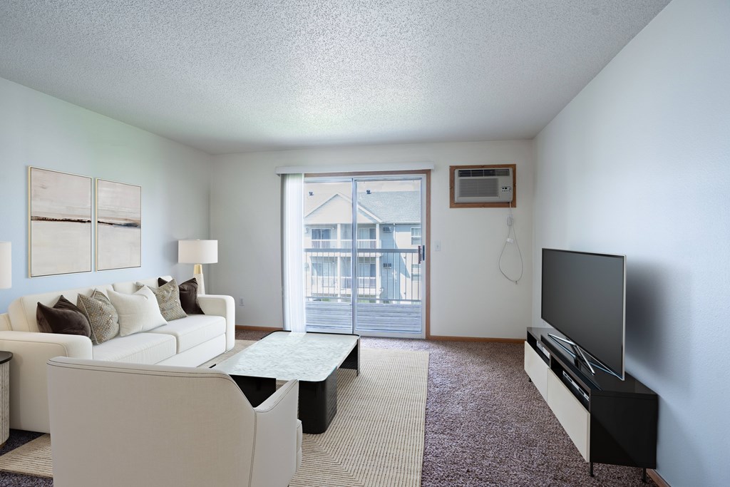 A living room with a white couch and a flat screen TV. Fargo, ND Stonebridge Apartments