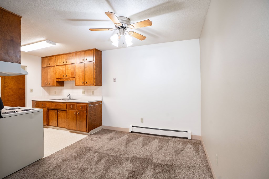 A room with a ceiling fan and a rug on the floor. Fargo, ND Islander Apartments