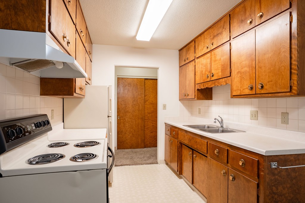 A kitchen with a white stove and wooden cabinets. Fargo, ND Islander Apartments