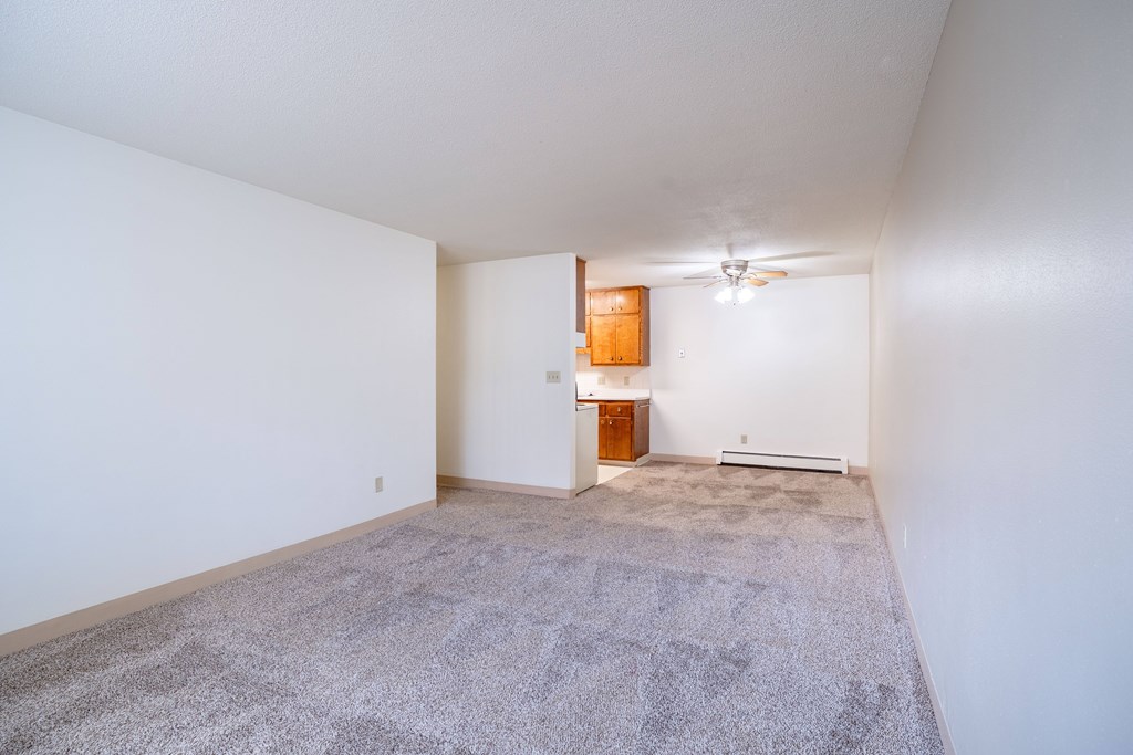 A room with a carpeted floor and a small wooden cabinet. Fargo, ND Islander Apartments