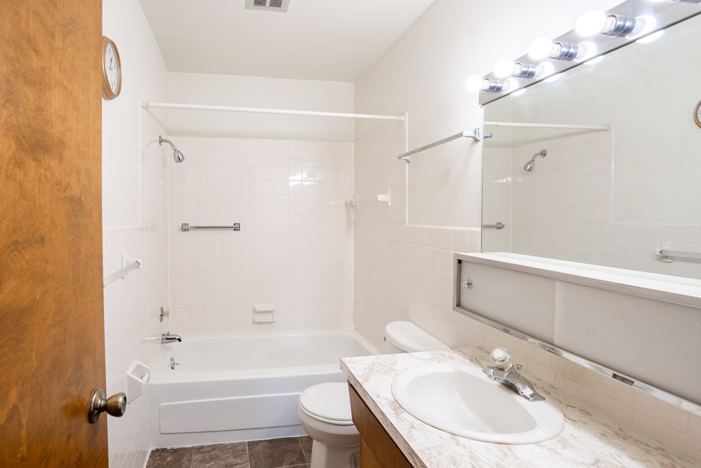 A bathroom with a toilet, sink, and bathtub. Fargo, ND Carr Apartments