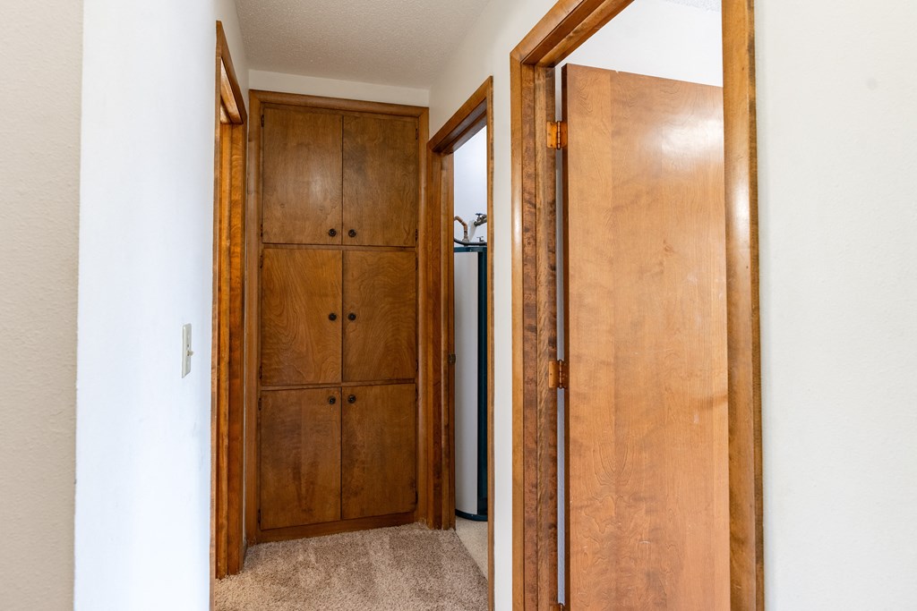 A brown wooden wardrobe is open to a white hallway. Fargo, ND Carr Apartments
