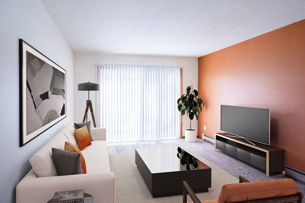 A living room with a white couch, a coffee table, a television, and a plant. Fargo, ND Carr Apartments