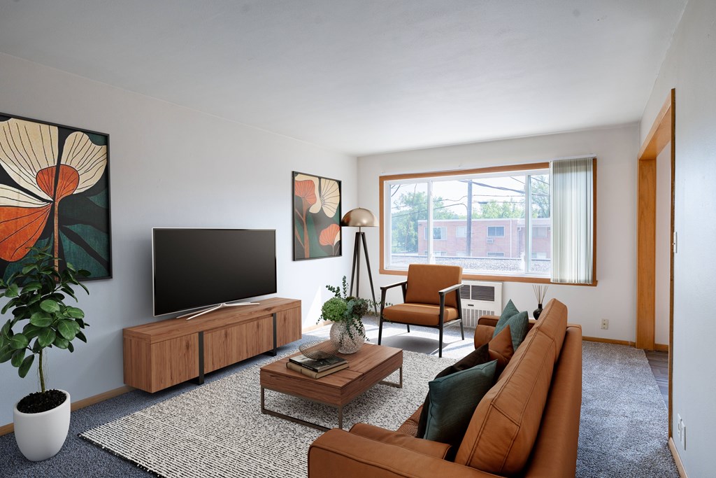 A living room with a brown couch, a coffee table, a television, and a potted plant. Fargo, ND L&R Apartments
