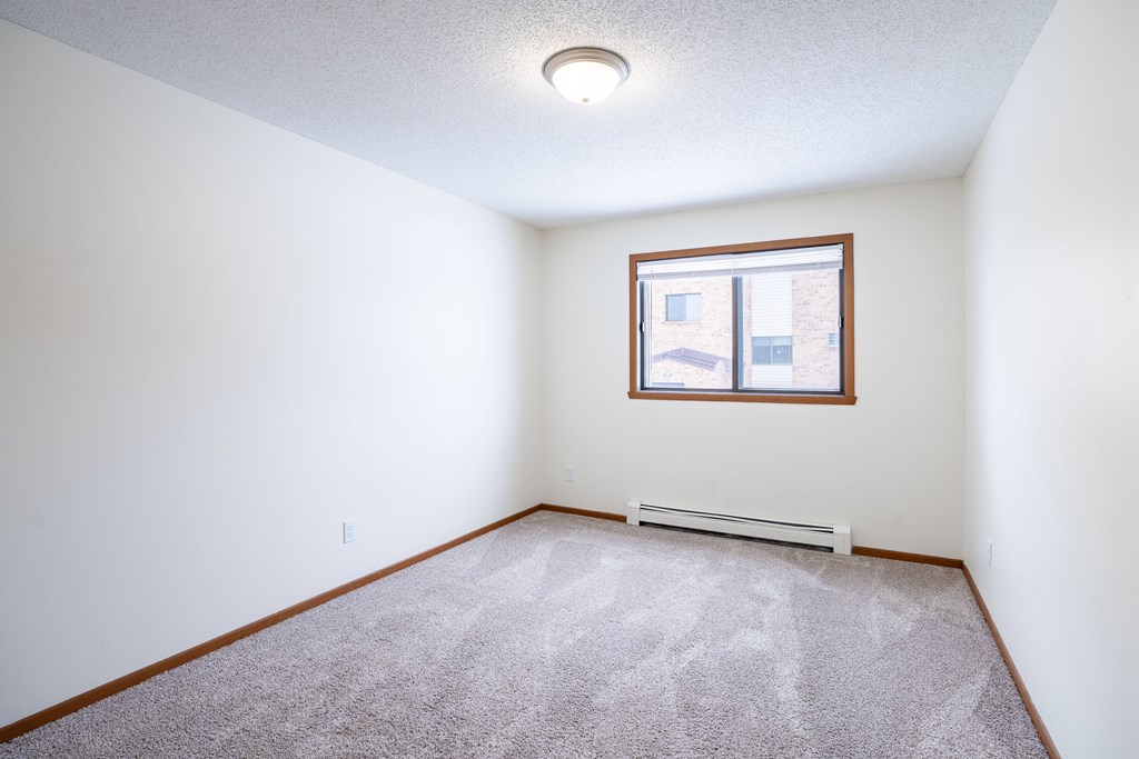 A room with a carpeted floor and a window. Fargo, ND Westwood Estates