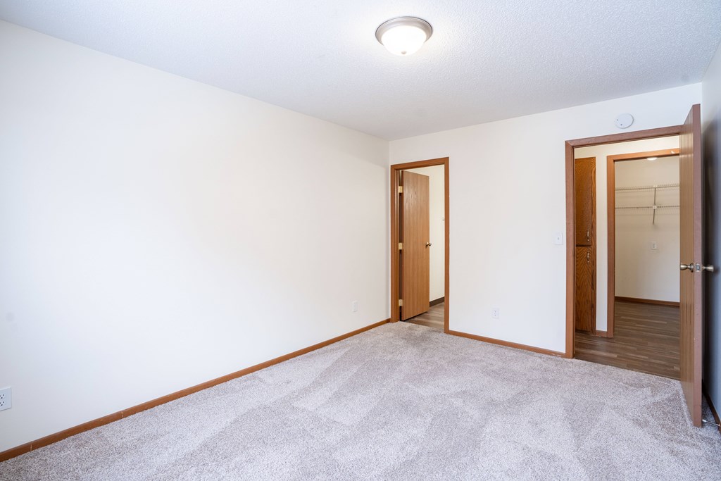 A room with a carpeted floor and two doors. Fargo, ND Westwood Estates
