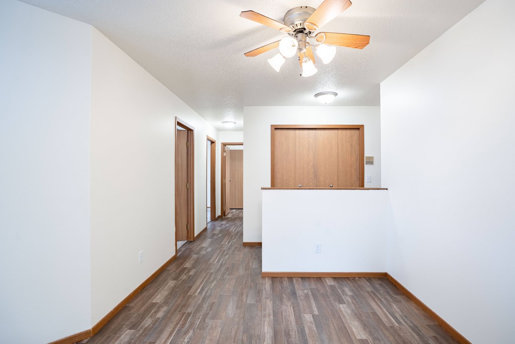 A long hallway with a fan and wood floors. Fargo, ND Westwood Estates
