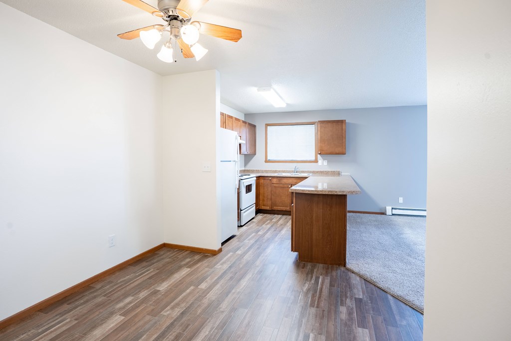 A room with a ceiling fan and wooden flooring. Fargo, ND Westwood Estates