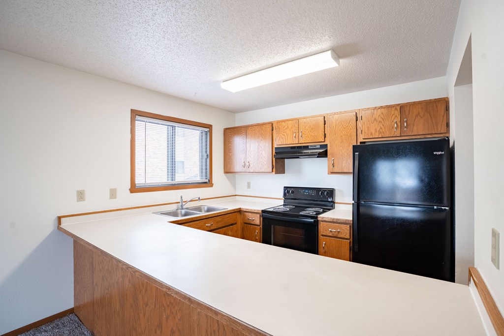 A kitchen with black appliances and wooden cabinets. Fargo, ND Westwood Estates
