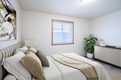 A bedroom with a large bed and a window. Moorhead, MN Woodstone Apartments