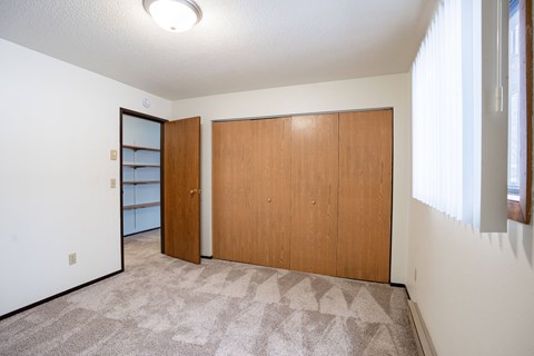 A room with a carpeted floor and two wooden doors.