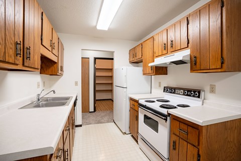 A kitchen with white appliances and wooden cabinets.