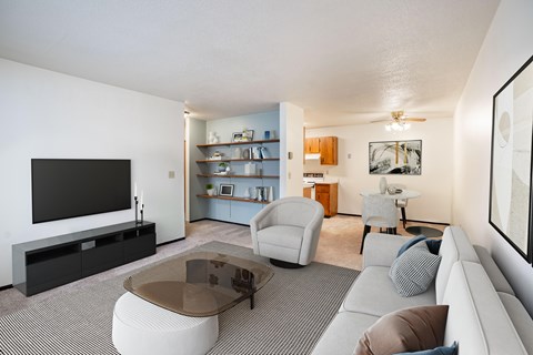 A living room with a grey sofa, a glass coffee table, and a television. Fargo, ND Countryside Apartments