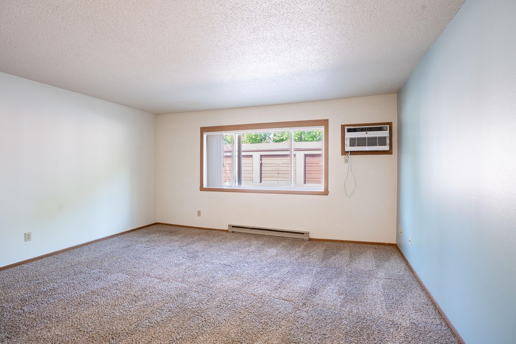 A room with a window and a carpet on the floor. Fargo, ND West Oak Apartments