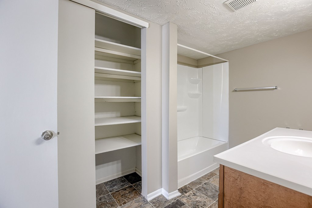 A white bathroom with a walk-in shower and a white sink. Omaha, NE Evergreen Terrace Apartments
