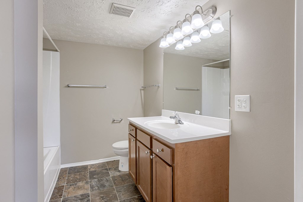 A bathroom with a sink, toilet, and mirror. Omaha, NE Evergreen Terrace Apartments