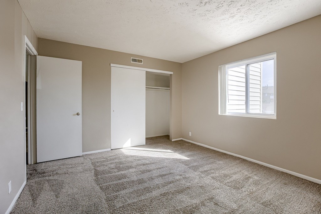 A room with a carpeted floor and a window with blinds. Omaha, NE Evergreen Terrace Apartments