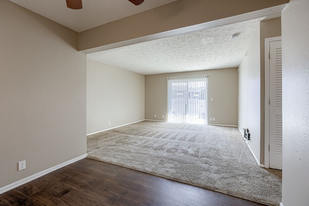 A room with a rug on the floor and a window with blinds. Omaha, NE Evergreen Terrace Apartments
