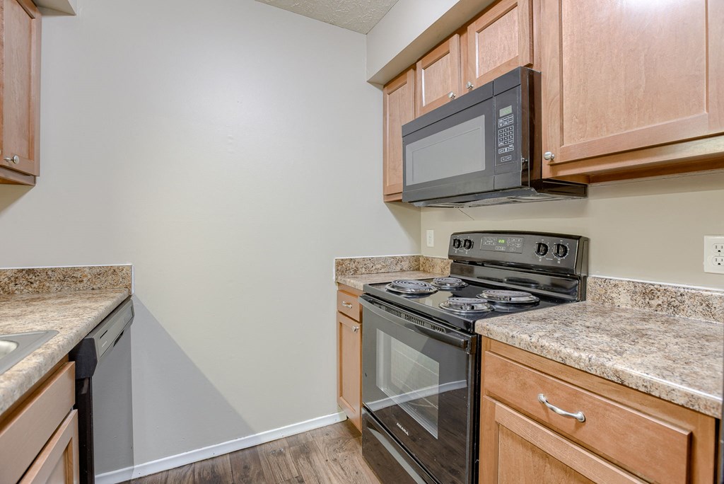 A kitchen with a black stove top oven and microwave above it. Omaha, NE Evergreen Terrace Apartments