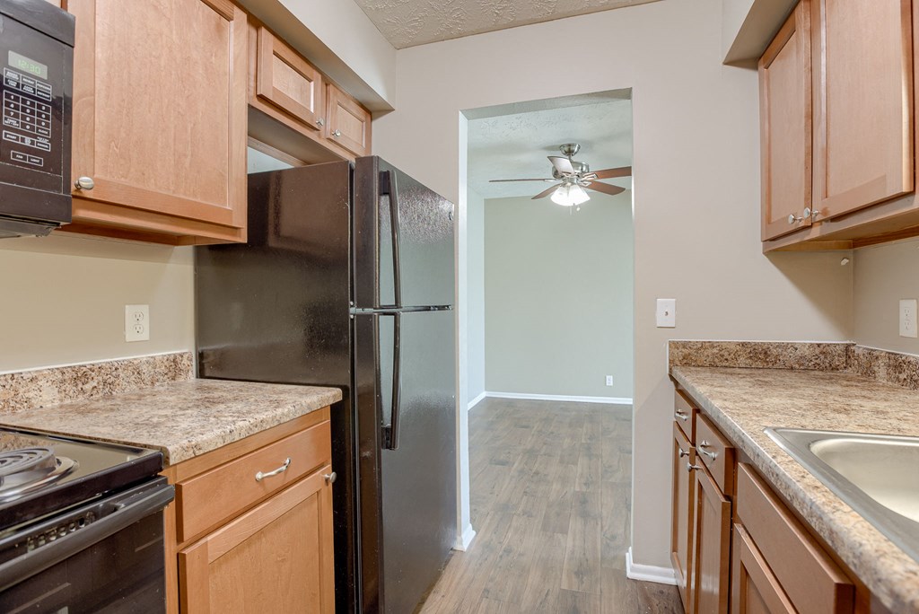 A kitchen with a black refrigerator and wooden cabinets. Omaha, NE Evergreen Terrace Apartments