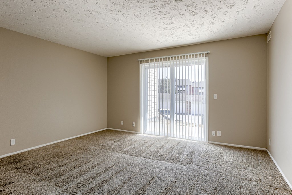 A room with a carpeted floor and a sliding glass door. Omaha, NE Evergreen Terrace Apartments