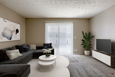 A living room with a grey couch, a white coffee table, and a painting on the wall.