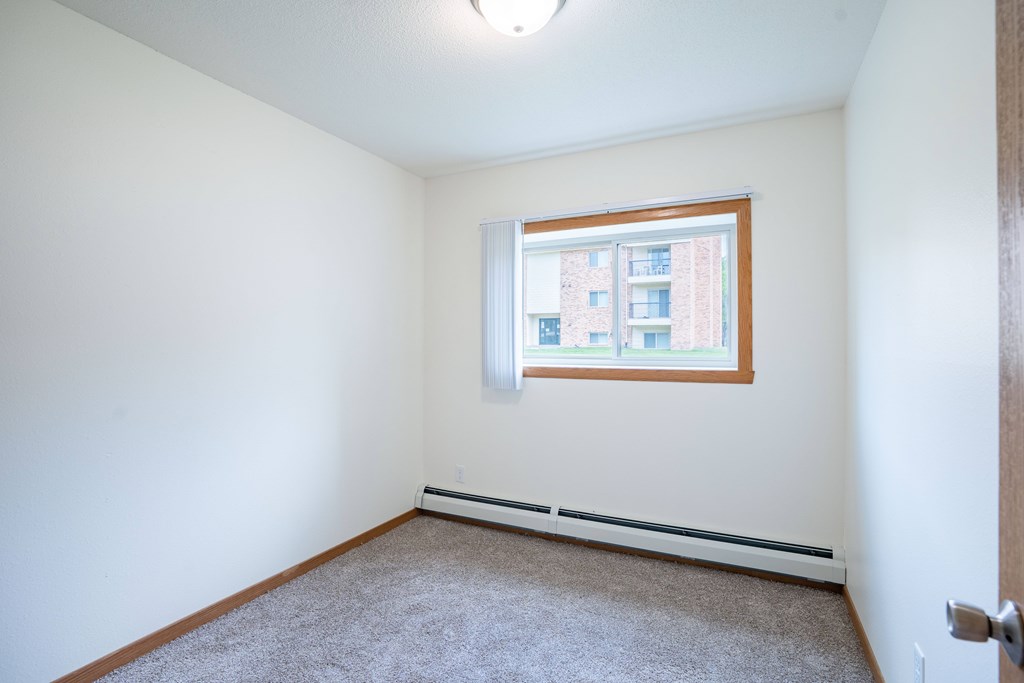 A room with a window and a carpeted floor. Grand Forks, ND Columbia West Apartments