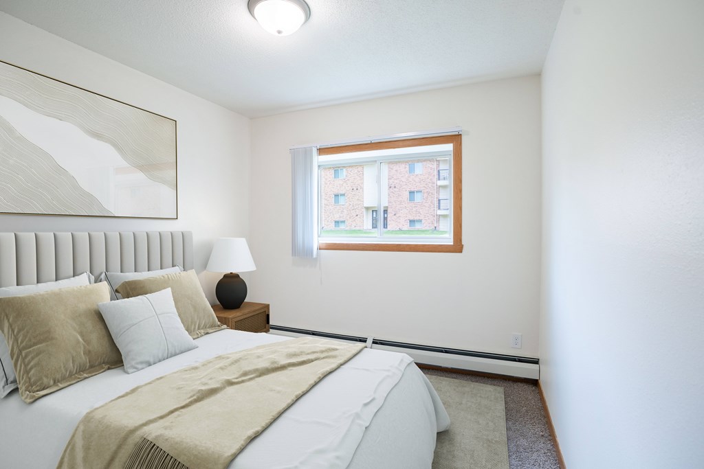 A bedroom with a large bed and a window. Grand Forks, ND Columbia West Apartments