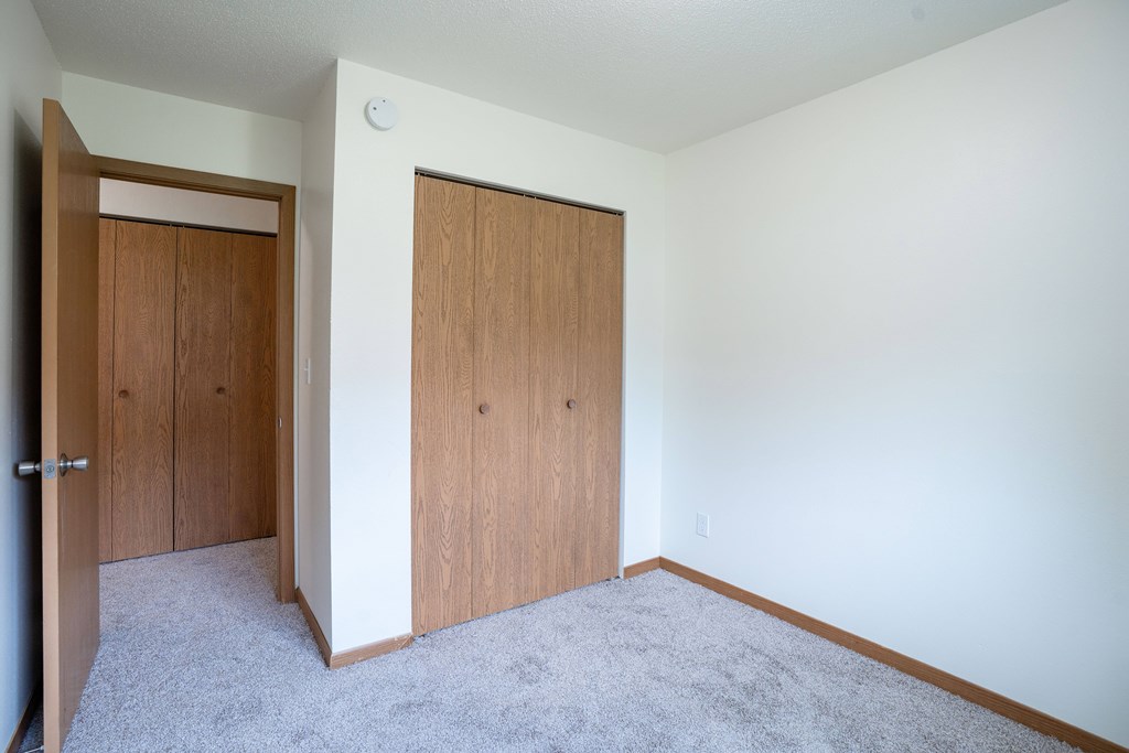 A room with a white wall and a brown door. Grand Forks, ND Columbia West Apartments