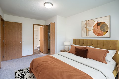 A bedroom with a large bed and a painting on the wall. Grand Forks, ND Columbia West Apartments