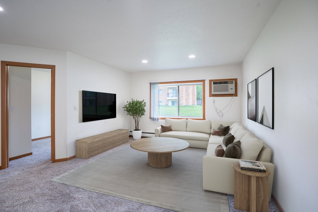 A living room with a couch, a coffee table, and a television. Grand Forks, ND Columbia West Apartments
