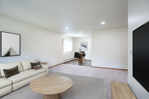 A living room with a white couch and a wooden coffee table.