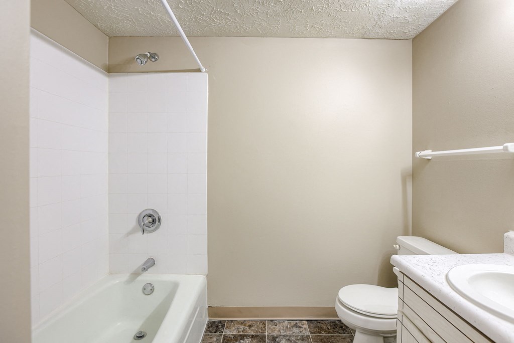 A white bathroom with a tub, toilet and sink. Omaha, NE Stony Brook Apartments