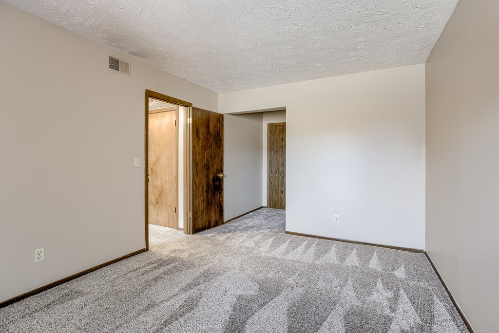 A room with a carpeted floor and two open doors. Omaha, NE Stony Brook Apartments