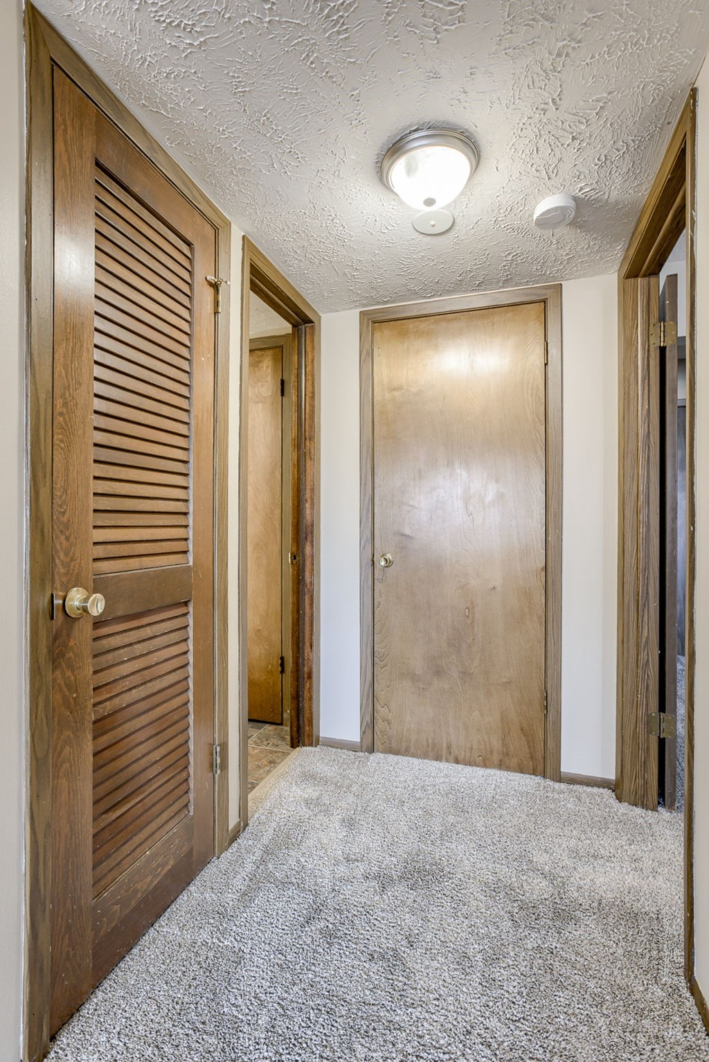A hallway with two doors and a carpeted floor. Omaha, NE Stony Brook Apartments