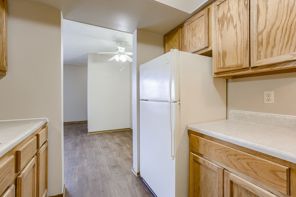 A kitchen with a white refrigerator and wooden cabinets. Omaha, NE Stony Brook Apartments