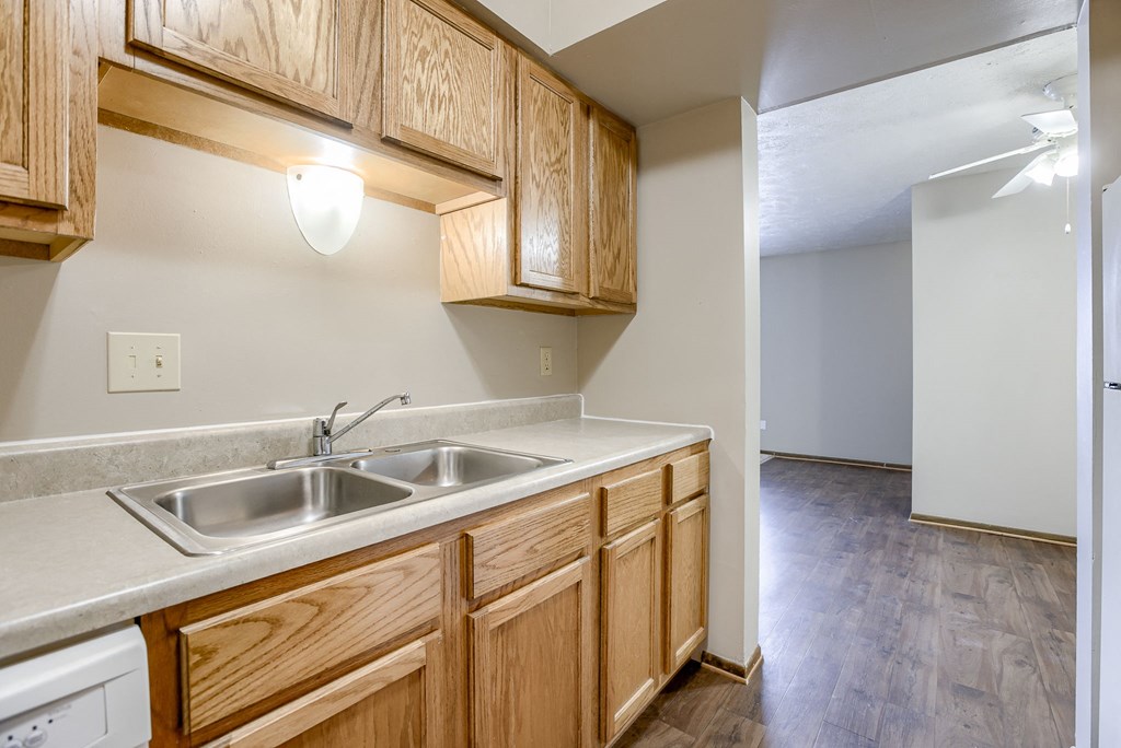 A kitchen with wooden cabinets and a white dishwasher. Omaha, NE Stony Brook Apartments