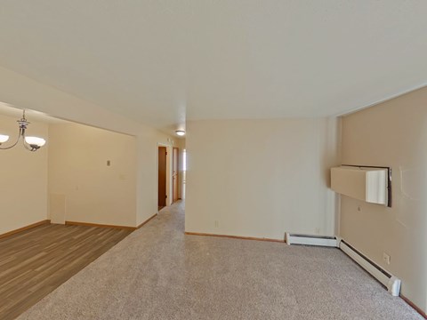 A spacious room with a carpeted floor and a wall-mounted air conditioner unit.