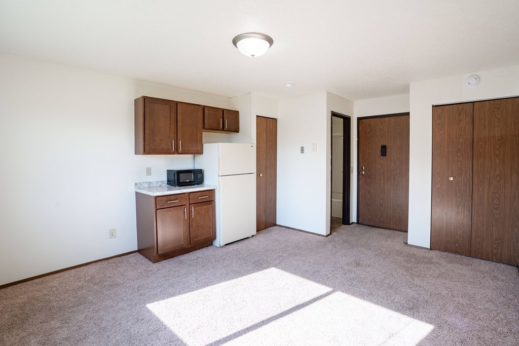 Fargo, ND Pacific Park I Apartments | 01A | Living A kitchen with white appliances and brown cabinets. Fargo, ND Pacific Park I Apartments
